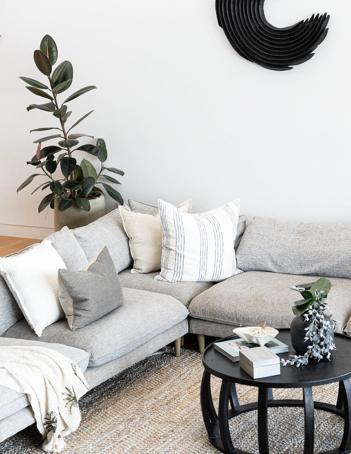 Corner of staged living room with sofa, plant and decor in Newcastle